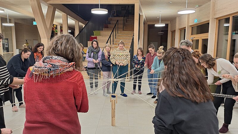 Kursteilnehmer halten im Kreis stehend Schnüre beim Turmspiel