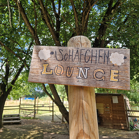 Wegweiser auf Holz zur Schäfchen Lounge