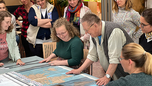 Kursteilnehmer:innen schauen eine Weltkarte an